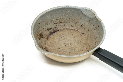 Small modern saucepan with burning mark on the surface, modern pan with black handle, 45-degree angle view, the image on white background.