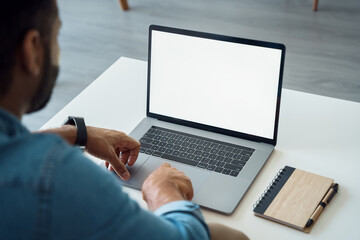Over shoulder view of white blank empty mockup laptop screen for advertising. Indian adult male student having virtual meeting, training online call, educational webinar, chatting or working at home