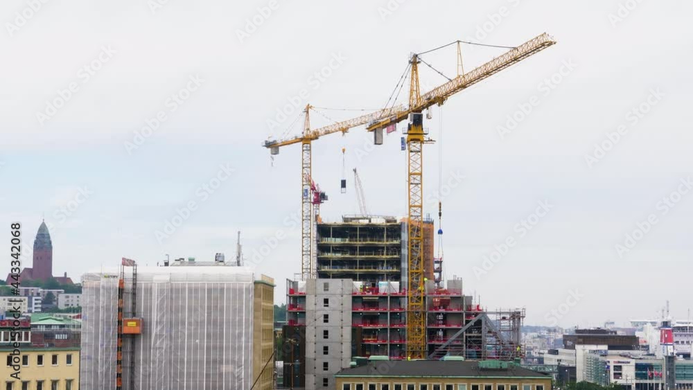 Tower Cranes At Work At The Construction Site In The City. medium shot Tower Cranes At Work At The Construction Site In The City. medium shot