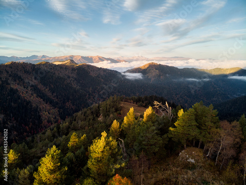 view from a drone at dawn in the mountains, aerial view through the clouds with fog