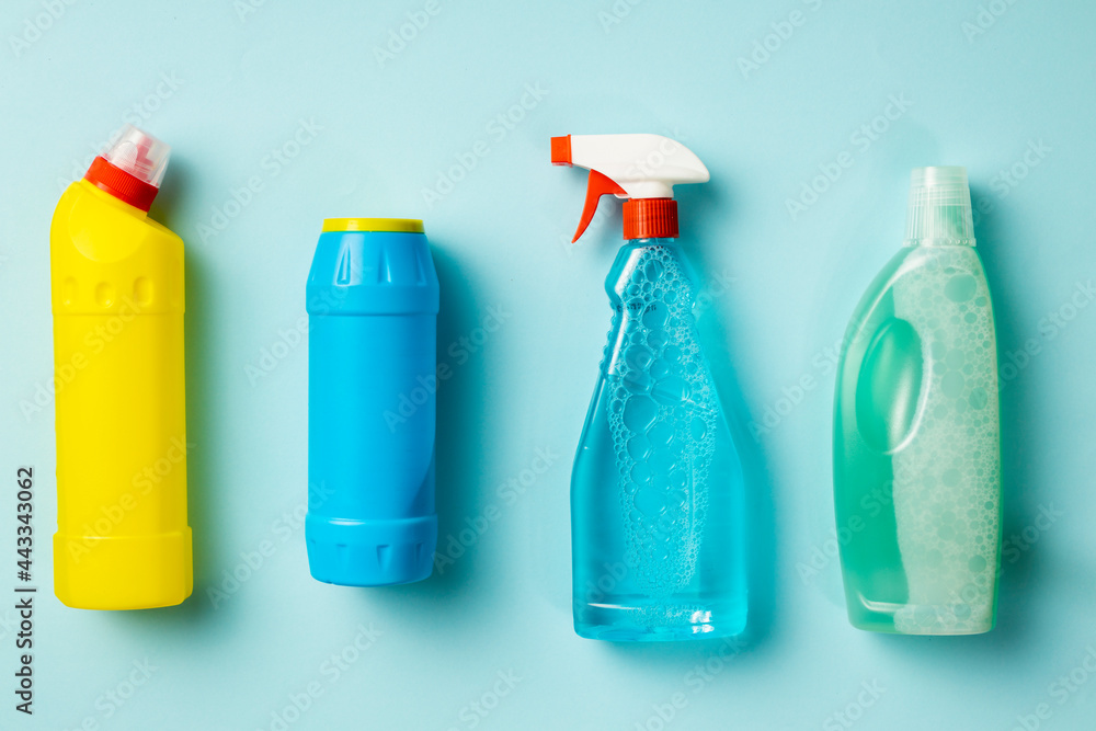 Various cleaning supplies, sprays and bottles on blue background, top view. House cleaning concept Various cleaning supplies, sprays and bottles on blue background, top view. House cleaning concept