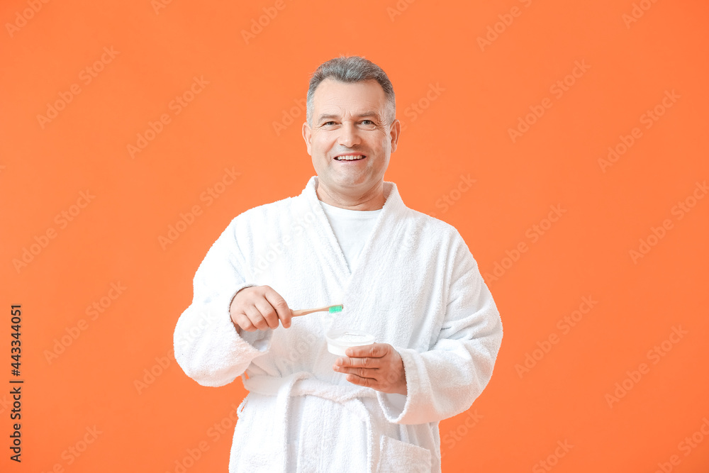 Mature man brushing teeth on color background Mature man brushing teeth on color background