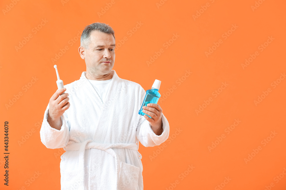 Mature man with tooth brush and mouth rinse on color background Mature man with tooth brush and mouth rinse on color background