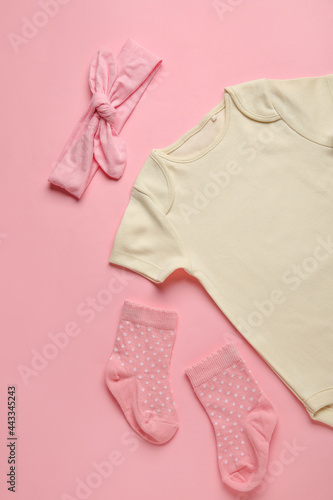 Baby clothes and socks on color background