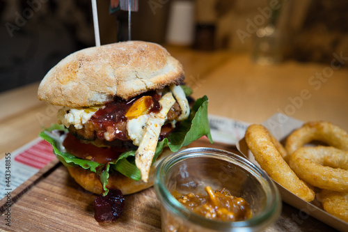 Selbstgemachter mega Burger mit Salat, Tomate, Dip und hausgemachten Zwiebelringen