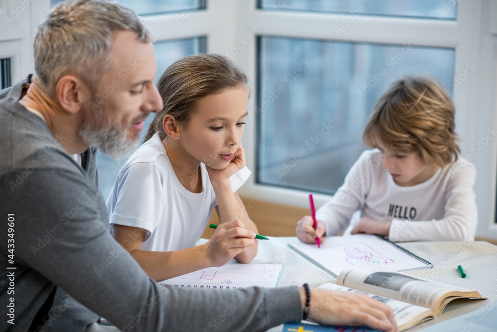Father helping kids with lessons and explaining them something Father helping kids with lessons and explaining them something