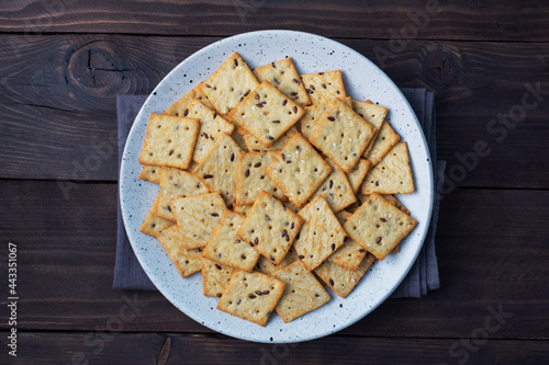 Delicious healthy cookies crackers with flax seeds and sesame seeds on a plate. Background of a healthy snack food, dark rustic wooden table. Copy space.