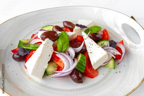 Greek salad in plate on white wooden background