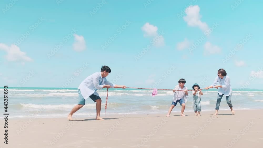 Father and family happily playing ropes on the beach in the morning sun. Father and family happily playing ropes on the beach in the morning sun.