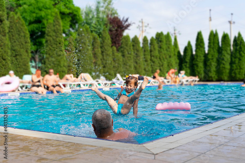 father and daughter have fun in the outdoor pool on a summer day