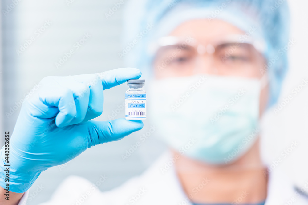 Young doctor or scientist in uniform wearing a face mask showing up coronavirus vaccine, nurse man holding bottle COVID-19 vaccination at laboratory, Healthcare And Medical concept Young doctor or scientist in uniform wearing a face mask showing up coronavirus vaccine, nurse man holding bottle COVID-19 vaccination at laboratory, Healthcare And Medical concept