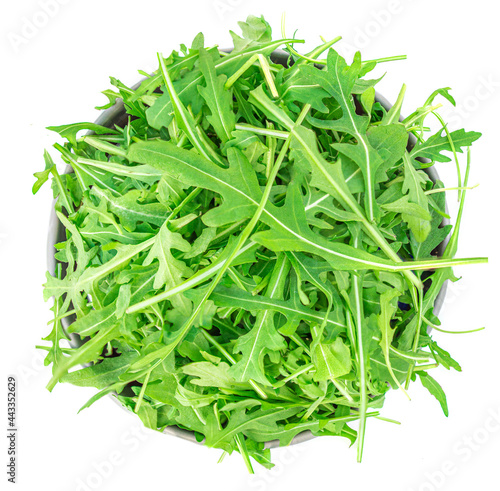 Rucola leaves in a bowl isolated on white background. Green fresh  Rocket salad or arugula leaf, top view.