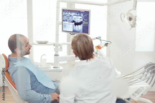 Dentist doctor and patient looking at digital teeh x-ray in stomatology hospital office. Sick patient sitting on dental chair preparing for dentistry surgery during somatology appointment