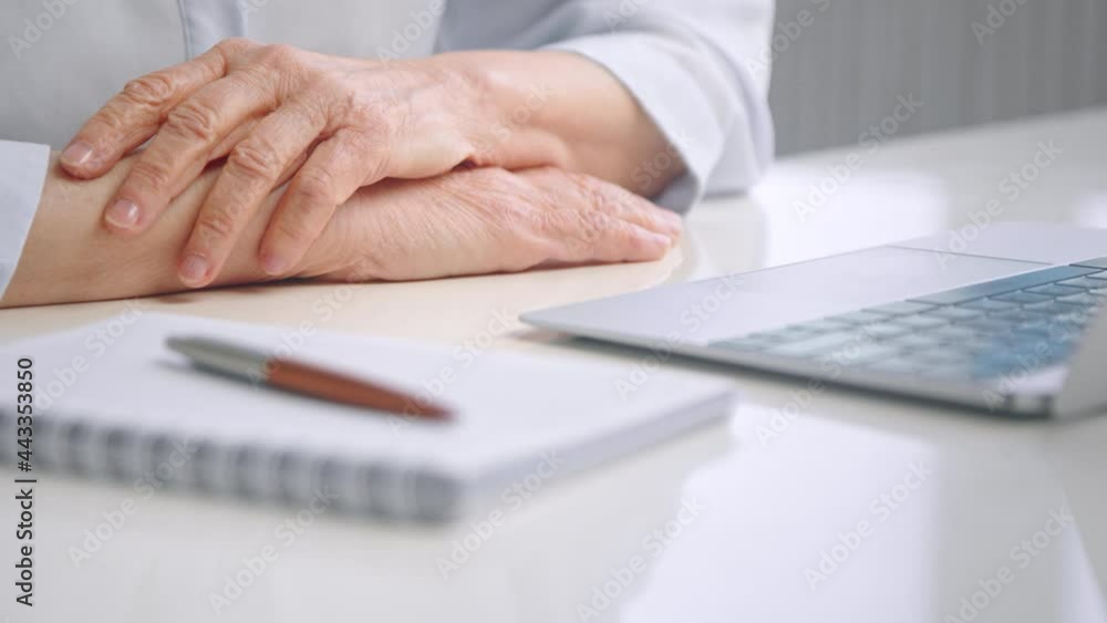 Senior woman puts overworked folded wrinkly hands on table Senior woman puts overworked folded wrinkly hands on table