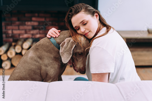 woman playing with her dog in the living room photo