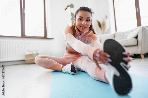 Fototapeta Naklejka Na Ścianę i Meble -  Young fit woman doing stretching exercises at home