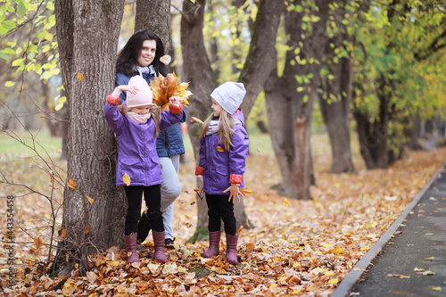 Young family on a walk in the autumn park on a sunny day. Happiness to be together.