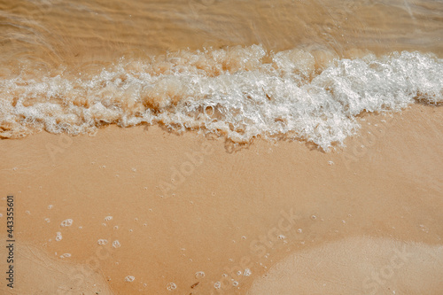Sand on the beach with champagne color. Close up top view. Clean sea shore. A natural backdrop of water and sand