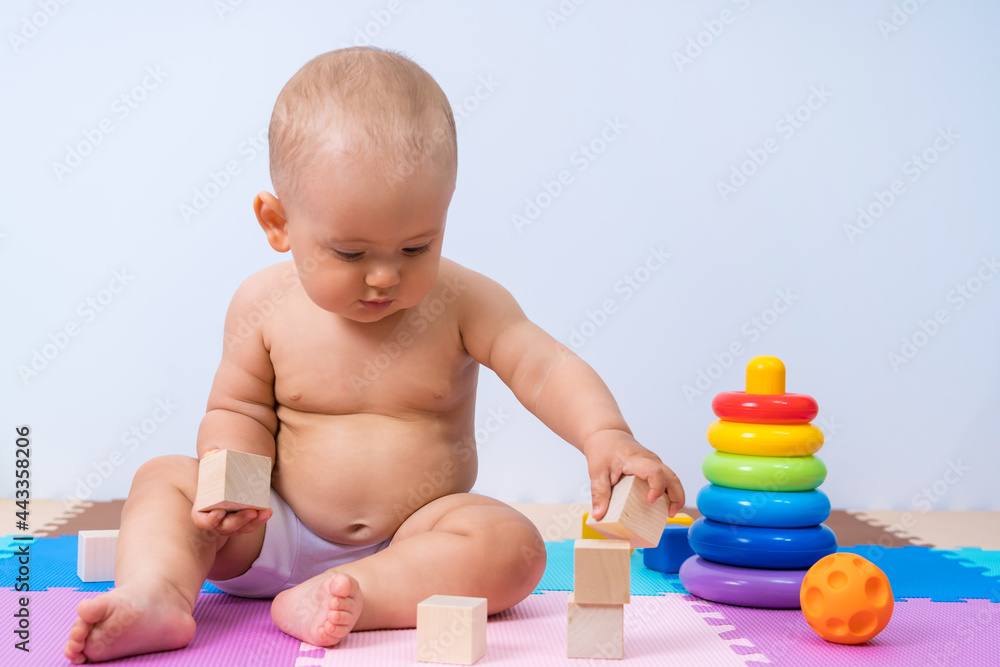 A child of 8-12 months assembles a tower of wooden cubes A child of 8-12 months assembles a tower of wooden cubes
