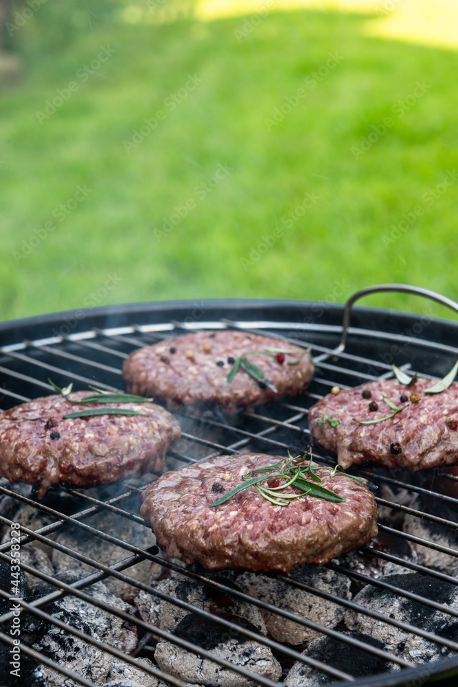 Meat Burgers Grilled on Charcoal BBQ Barbecque in Backyard Garden at Summer Picnic Meat Burgers Grilled on Charcoal BBQ Barbecque in Backyard Garden at Summer Picnic