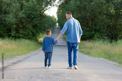 father and son walk along the road holding hands © Kostia
