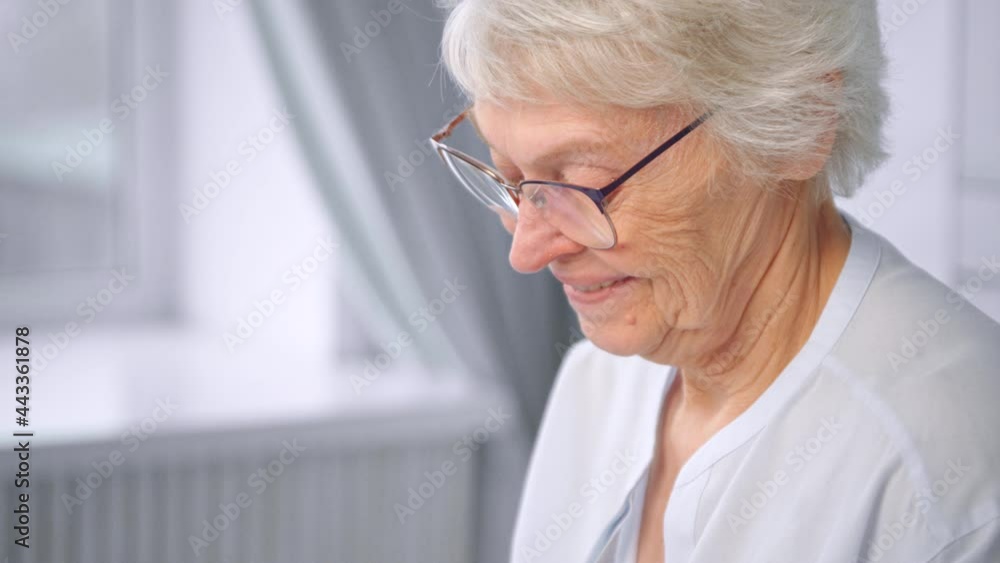 Grey haired old woman company manager looks down smiling Grey haired old woman company manager looks down smiling