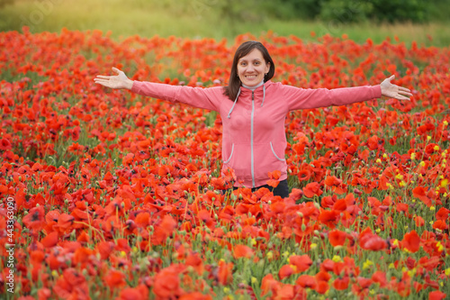 Cute young woman in big meadow of poppies.