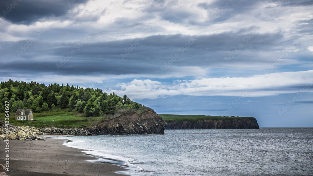 Typical landscape of the northern shore of the Gaspesie Peninsula, along the route 132, with cliffs, coves and beachs and small houses (Quebec, Canada)