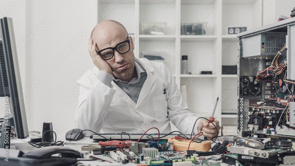 Frustrated exhausted technician repairing a computer