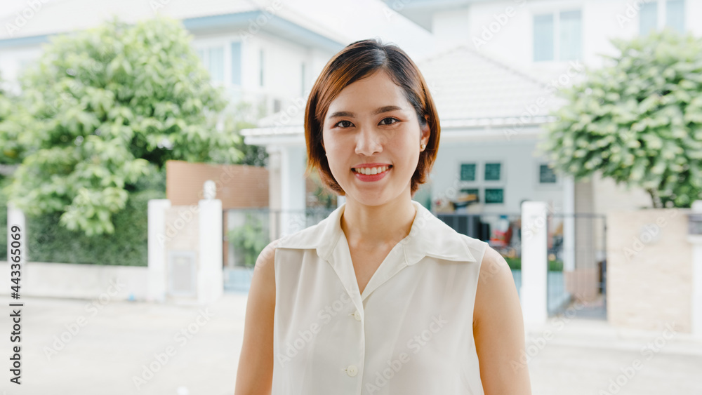 Happy young Asian female feeling happy smiling and looking to camera while relax on street in modern city. Lifestyle woman at outside house concept.