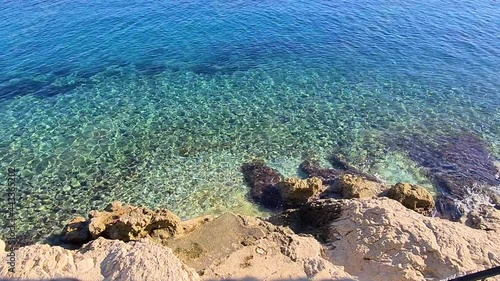 Blue turquoise shimmering water at a rocky beach reflecting sun
