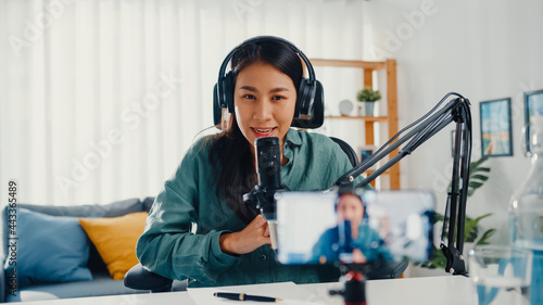 Canvas-taulu Teenage Asia girl influencer use microphone wear headphone record content with smart phone for online audience listen at house