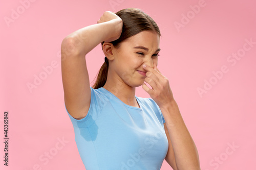 woman in blue t-shirt sweaty armpit bad smell pink background photo
