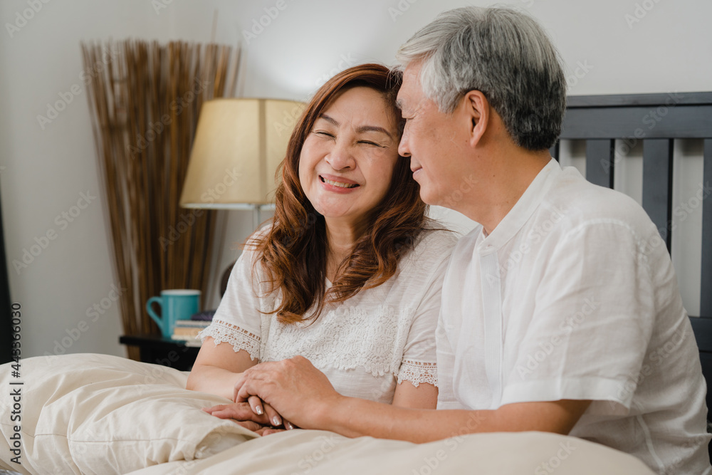 Asian senior couple talking on bed at home. Asian Senior Chinese grandparents, husband and wife happy relax together after wake up while lying on bed in bedroom at home in the morning concept. Asian senior couple talking on bed at home. Asian Senior Chinese grandparents, husband and wife happy relax together after wake up while lying on bed in bedroom at home in the morning concept.