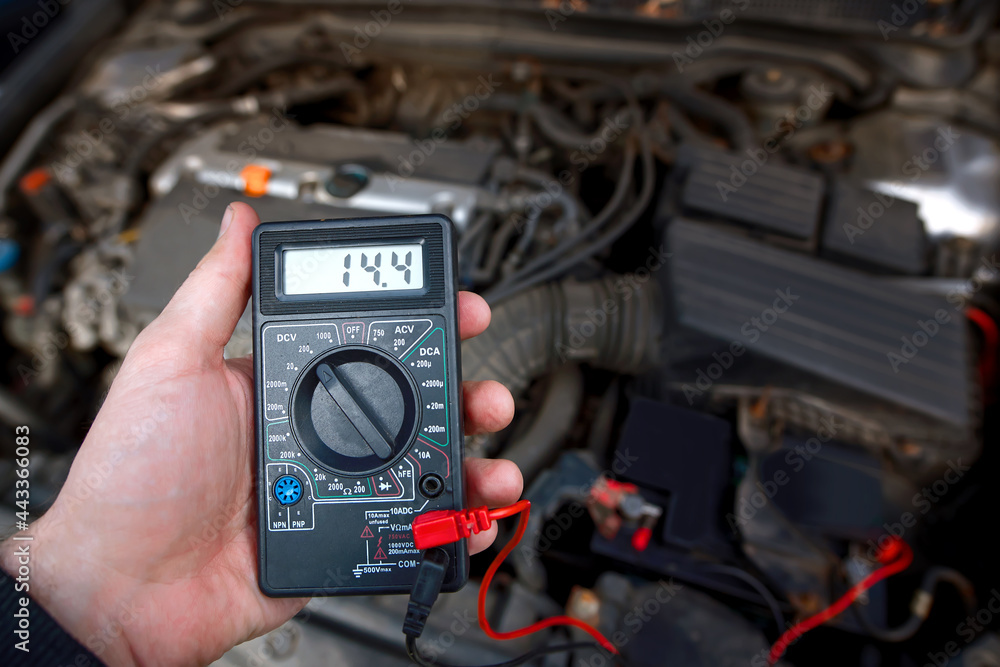 Foto de Man test car alternator with multimeter, start engine and check