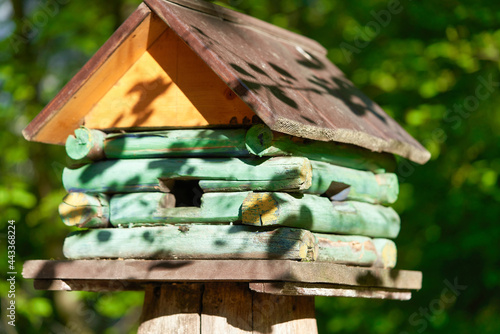 Wooden birdhouse in the form of a house on a stump in the park
