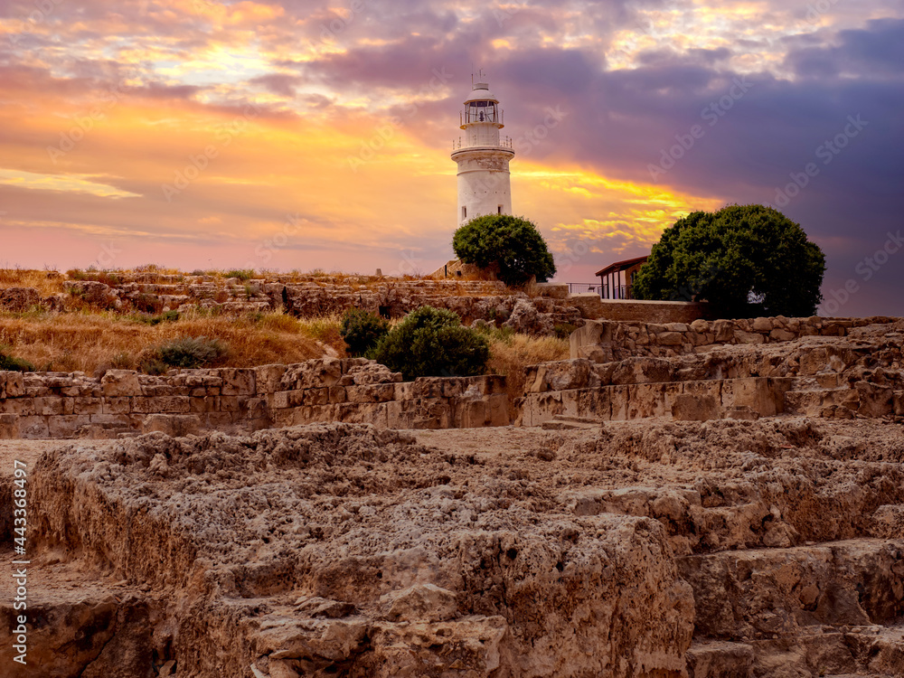 Cyprus landscape. Lighthouse on banks of city of Paphos. White lighthouse next to medieval ruins. Attractions of city of Paphos. Cyprus island at sunset. Holidays in Republic of Cyprus