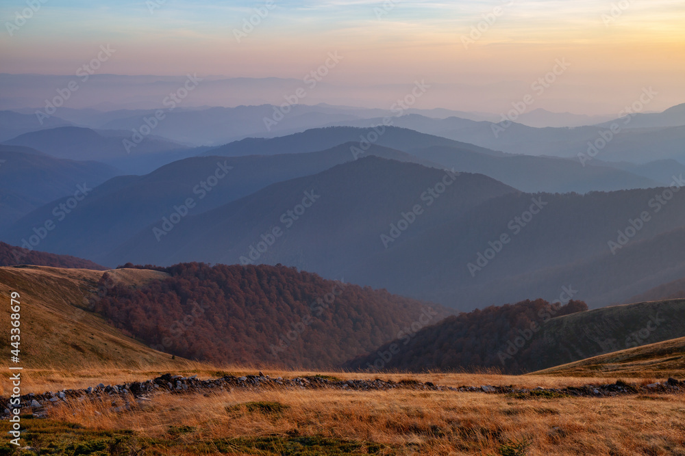 Sunrise. Autumn morning. Fall scene. Landscape with high mountains. Panoramic view. Natural landscape. The lawn with orange grass. Autumnal wallpaper background. Touristic place Carpathian park.