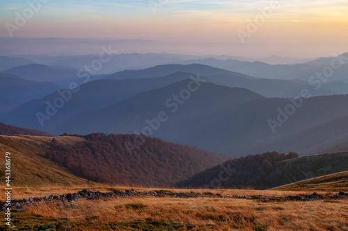 Sunrise. Autumn morning. Fall scene. Landscape with high mountains. Panoramic view. Natural landscape. The lawn with orange grass. Autumnal wallpaper background. Touristic place Carpathian park.
