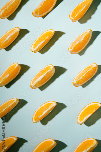 Isolated slices of orange on a light blue background with contrasting shadows