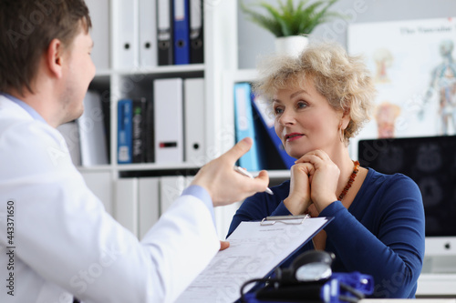 Elderly woman sitting at table at doctor appointment in clinic