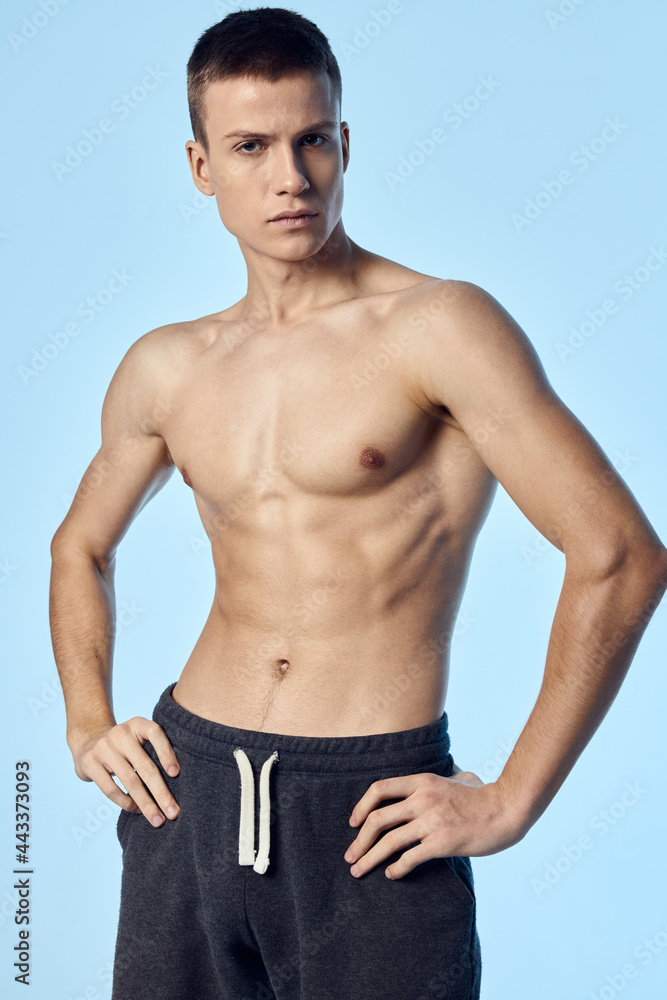 Fototapeta premium athletic man with a naked torso hold hands on the belt bodybuilder blue background
