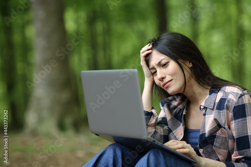 Mixed race sad woman checking laptop