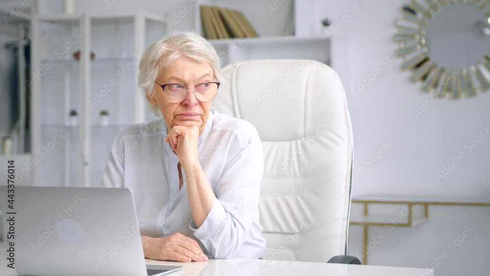 Bored old lady with grey hair looks into display with anger Bored old lady with grey hair looks into display with anger