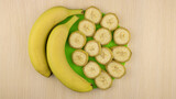 The bananas pieces are laid out on a green stand. Two whole bananas next to each other. Top view.