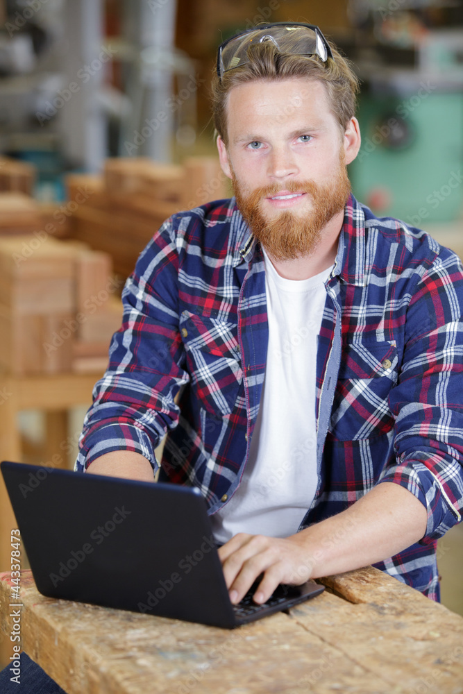smiling male worker in workshop with laptop smiling male worker in workshop with laptop