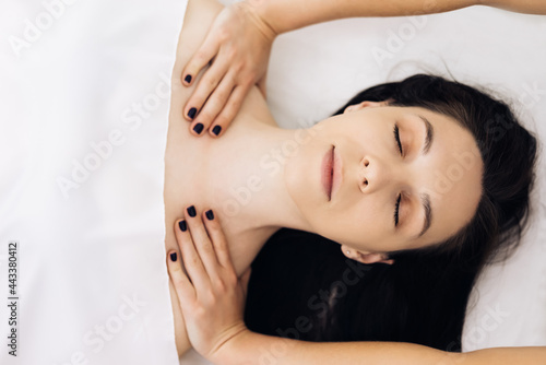 Top view of Young caucasian woman getting spa massage treatment at beauty spa salon. Face massage essential oil for skincare, Relaxing massage, Spa skin and body care