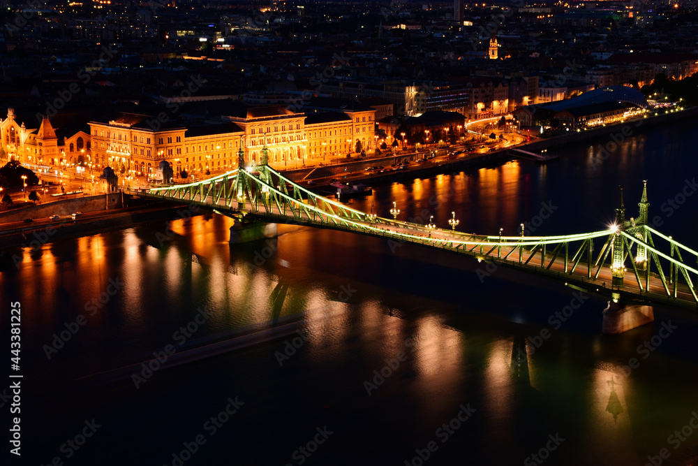 Fototapeta premium the Liberty bridge in Budapest. aerial evening view or blue hour. brightly illuminated steel structure. reflection on water. tourism and travel concept. transportation and design. night photo