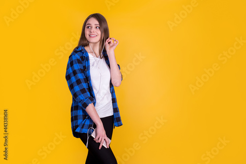 Beautiful fascinating girl in a blue shirt on a yellow background