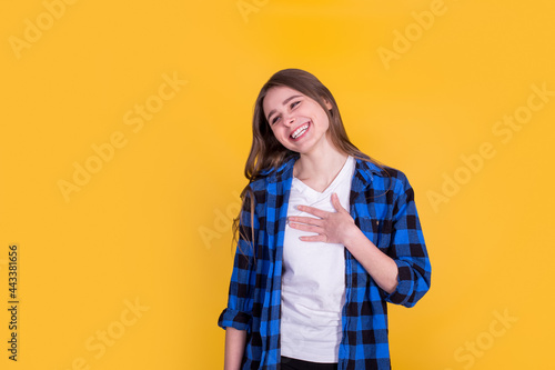 Beautiful happy girl in a blue shirt on a yellow background